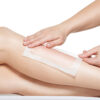 woman depilating her legs by waxing -  studio on white background